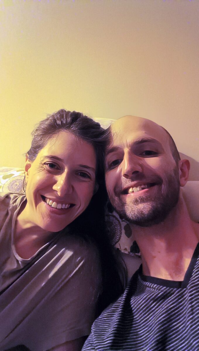 My wife and me on the couch, indoors — soft, grainy, and washed out