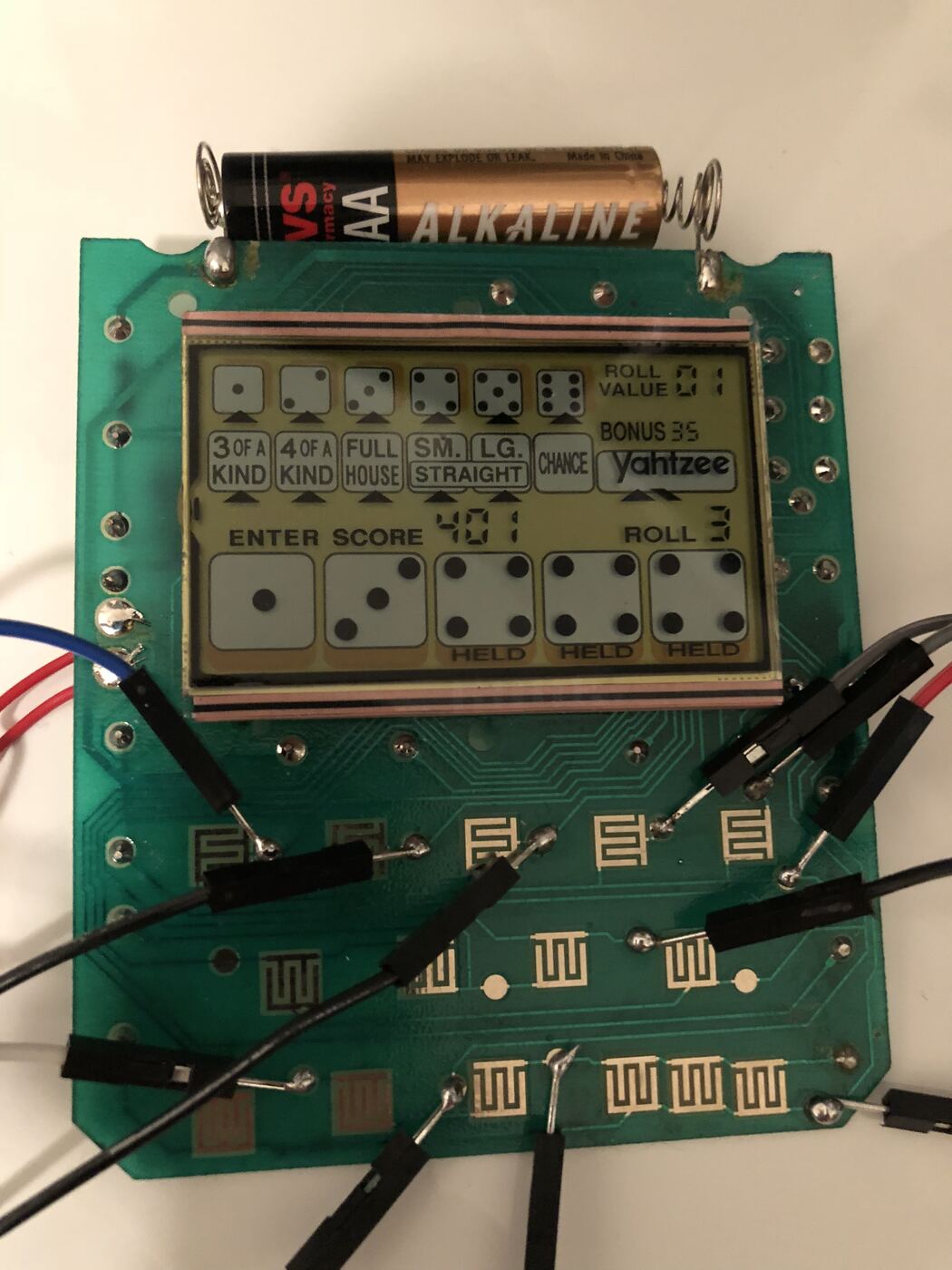 The handheld's board with jumper wires attached to the button contacts, LCD still running